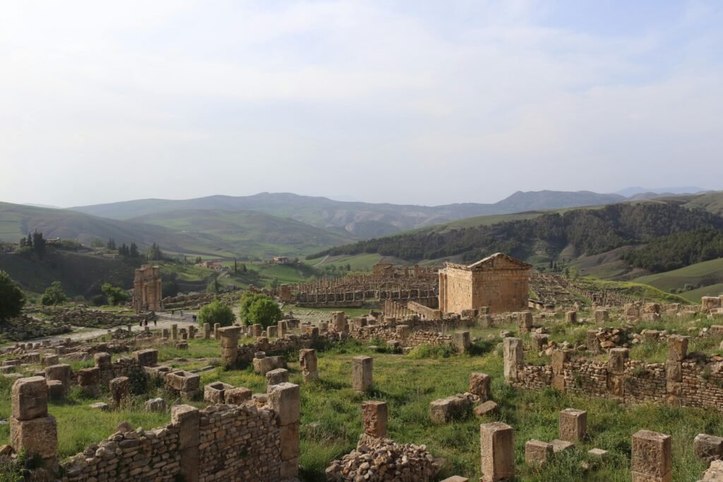 Stunning view of ancient Roman ruins at Djemila, bathed in natural light amidst rolling hills.