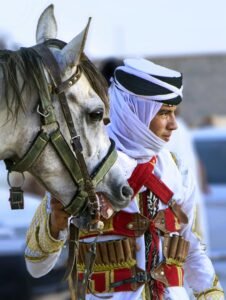 Algerian horseman in traditional attire with horse in Tébessa, Algeria.