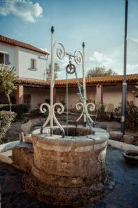 A picturesque stone wishing well in a serene Annaba courtyard under a clear blue sky.