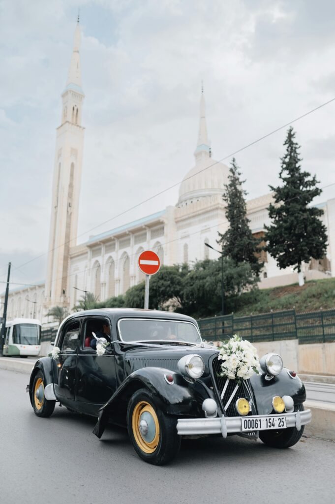 A classic vintage car with flowers parked in front of a mosque in Constantine, Algeria.