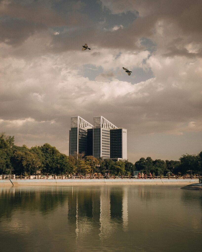Captivating view of Park Mall Setif with birds flying above and a nearby lake reflecting the cloudy sky.